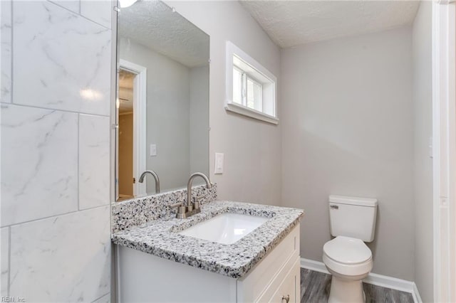 bathroom with vanity, a textured ceiling, hardwood / wood-style flooring, and toilet