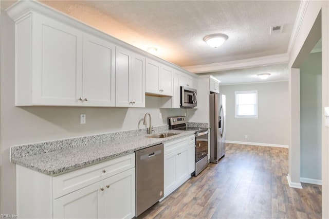 kitchen featuring appliances with stainless steel finishes, a textured ceiling, white cabinetry, and sink