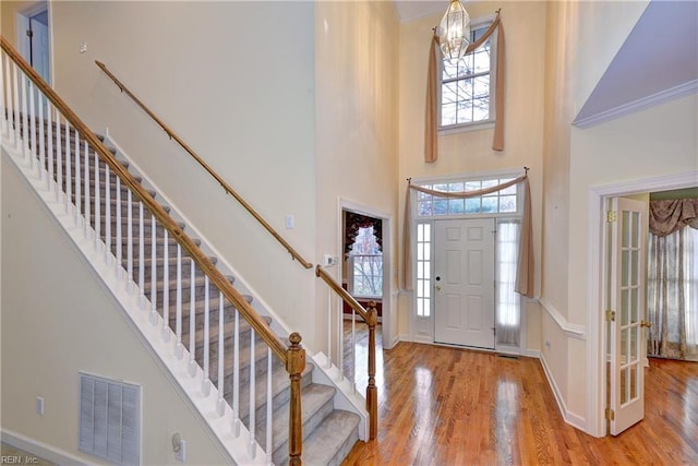 entryway featuring a towering ceiling, light hardwood / wood-style floors, and an inviting chandelier