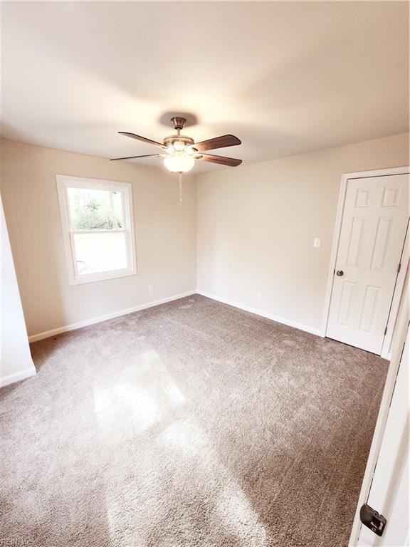 spare room with dark colored carpet and ceiling fan