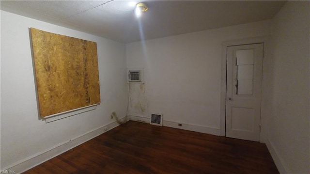 spare room featuring a wall unit AC and dark hardwood / wood-style flooring