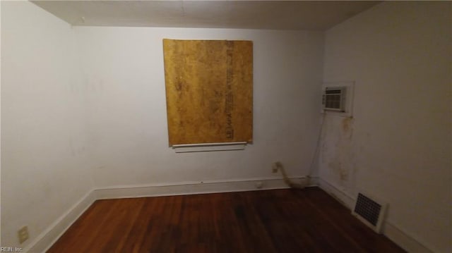 empty room featuring dark hardwood / wood-style flooring and a wall mounted AC