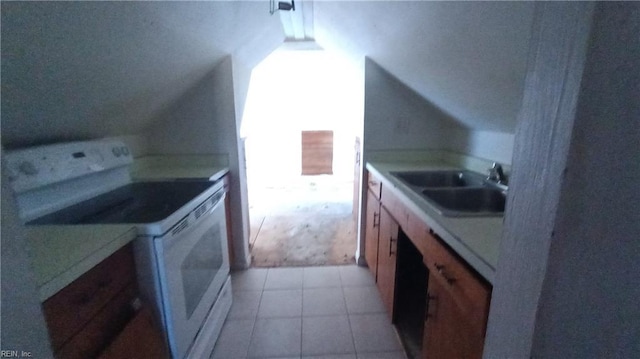 kitchen with white electric range, light tile patterned floors, vaulted ceiling, and sink