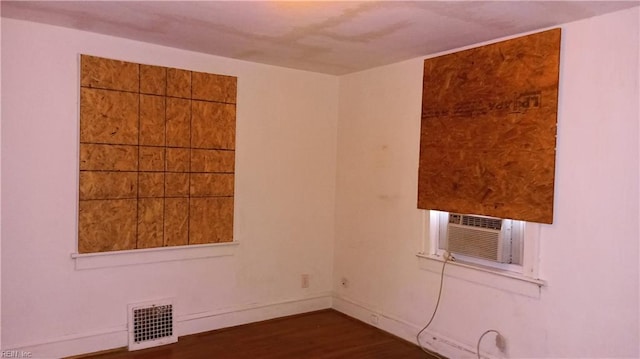 spare room featuring cooling unit and dark hardwood / wood-style flooring