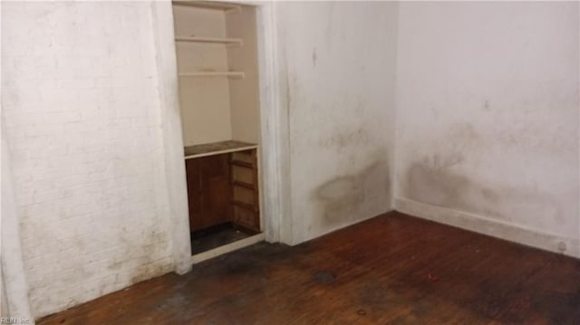 unfurnished bedroom featuring a spacious closet, a closet, and dark wood-type flooring