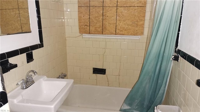 bathroom with sink, tile walls, and shower / tub combo with curtain