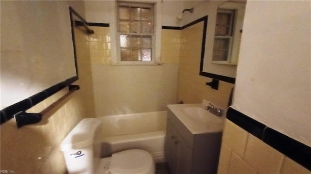 full bathroom with vanity, toilet, tiled shower / bath, and tile walls