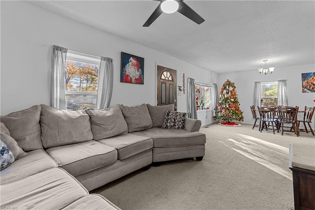 carpeted living room featuring ceiling fan with notable chandelier