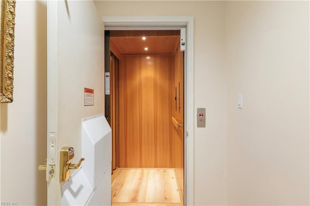 hallway with elevator and light wood-type flooring