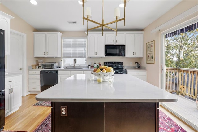 kitchen with a center island, black appliances, sink, light hardwood / wood-style flooring, and decorative light fixtures