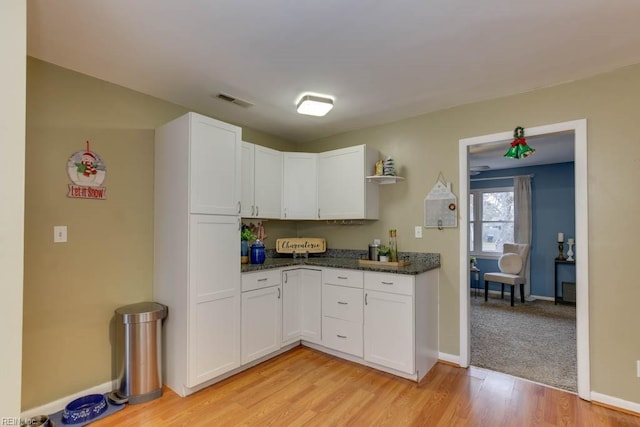 kitchen featuring light wood-type flooring, white cabinetry, and dark stone countertops