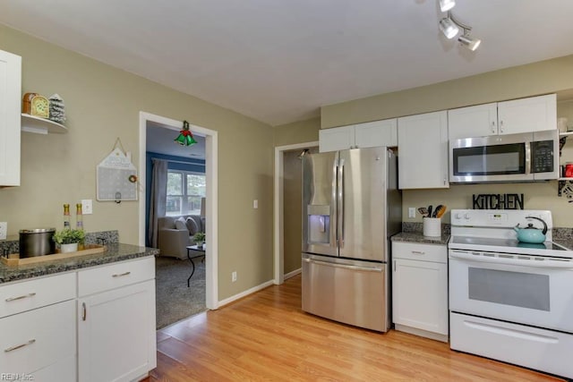 kitchen featuring appliances with stainless steel finishes, light hardwood / wood-style flooring, white cabinetry, and dark stone countertops