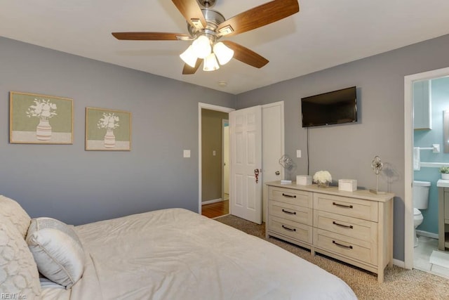 carpeted bedroom featuring ceiling fan and ensuite bath