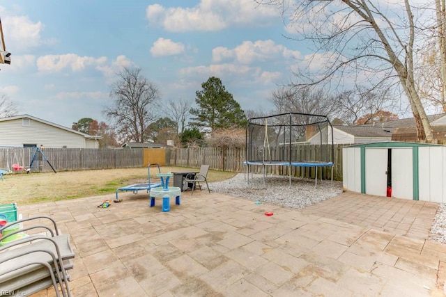 view of patio with a trampoline, a storage unit, and an outdoor fire pit