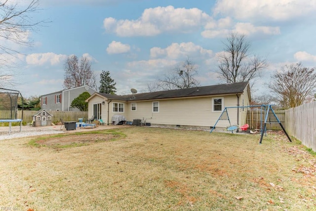 rear view of house with a playground, a yard, a patio, and a trampoline