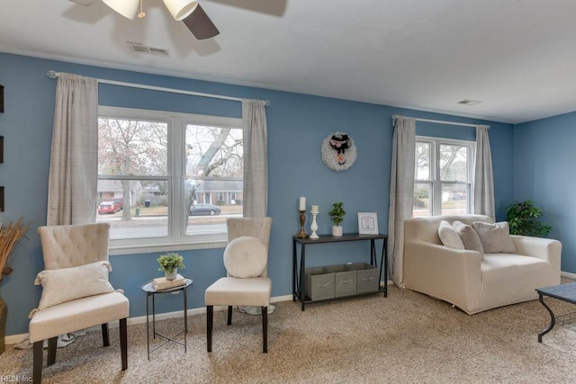 living area featuring plenty of natural light, ceiling fan, and light colored carpet