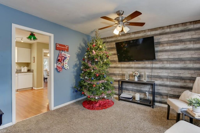 carpeted living room with wooden walls and ceiling fan