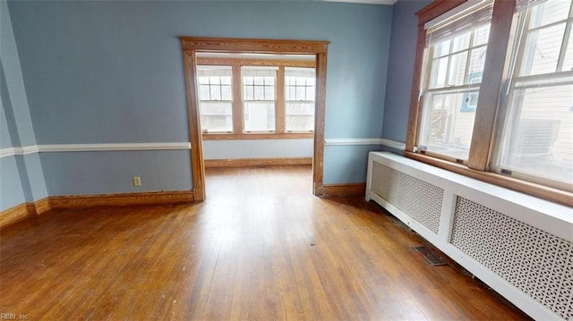 unfurnished room featuring radiator heating unit and hardwood / wood-style flooring