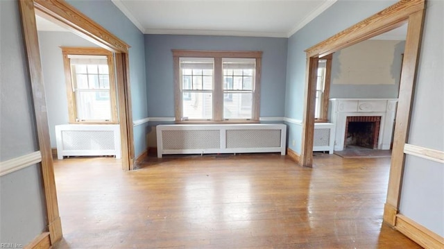 unfurnished living room featuring radiator heating unit, hardwood / wood-style flooring, and plenty of natural light