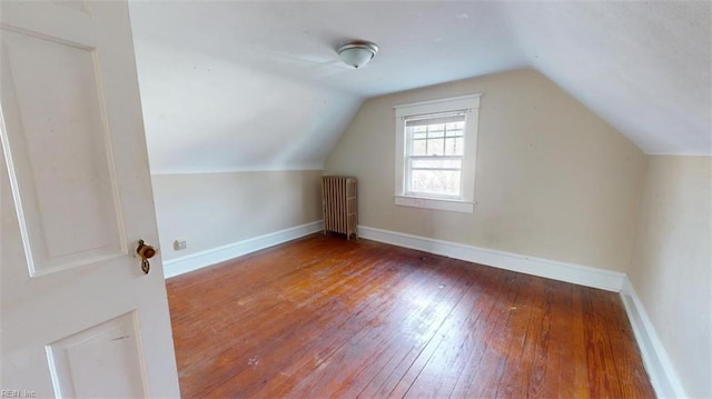 additional living space with radiator heating unit, wood-type flooring, and vaulted ceiling