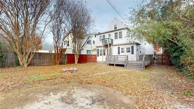 back of house with a wooden deck and a balcony