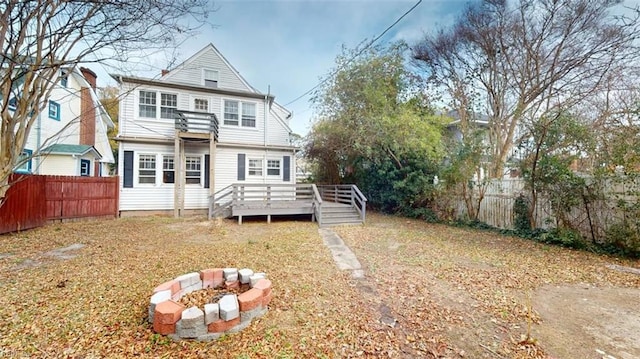 rear view of property featuring a wooden deck, a balcony, and a fire pit