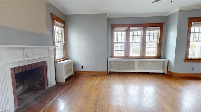 unfurnished living room with a wealth of natural light, radiator, and a brick fireplace