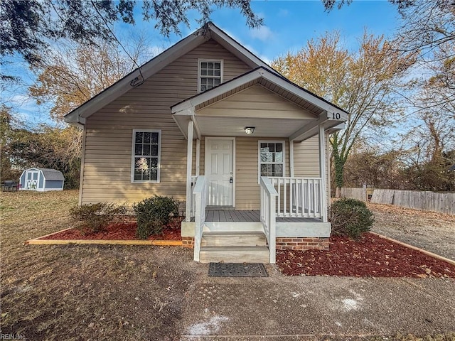 bungalow featuring a porch and a shed