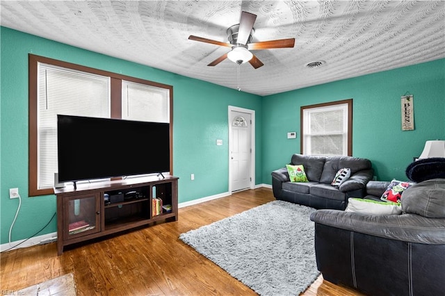 living room featuring ceiling fan, hardwood / wood-style floors, and a healthy amount of sunlight