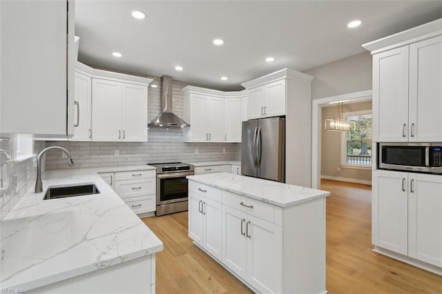 kitchen with white cabinets, appliances with stainless steel finishes, and wall chimney range hood