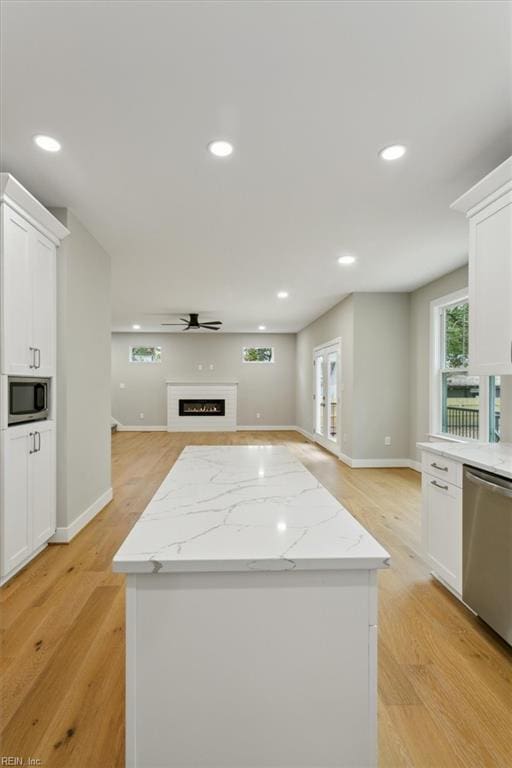 kitchen featuring white cabinets, light stone counters, light wood-type flooring, and stainless steel appliances