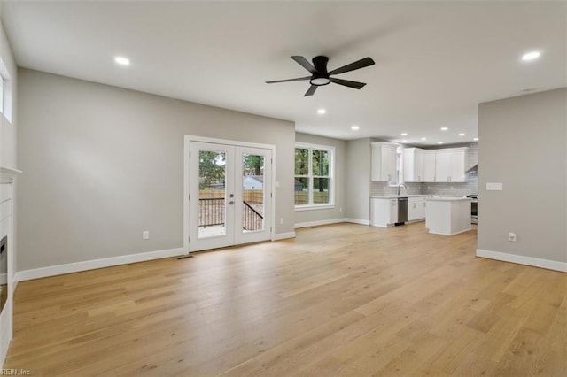 unfurnished living room featuring ceiling fan, french doors, and light hardwood / wood-style floors