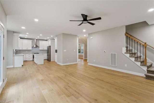 unfurnished living room with ceiling fan, sink, and light wood-type flooring