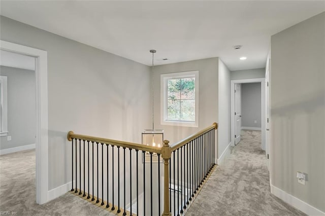 corridor featuring a chandelier and light colored carpet