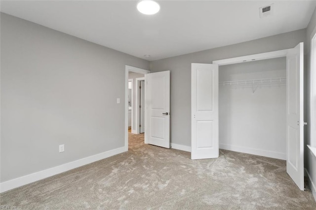 unfurnished bedroom featuring light carpet and a closet