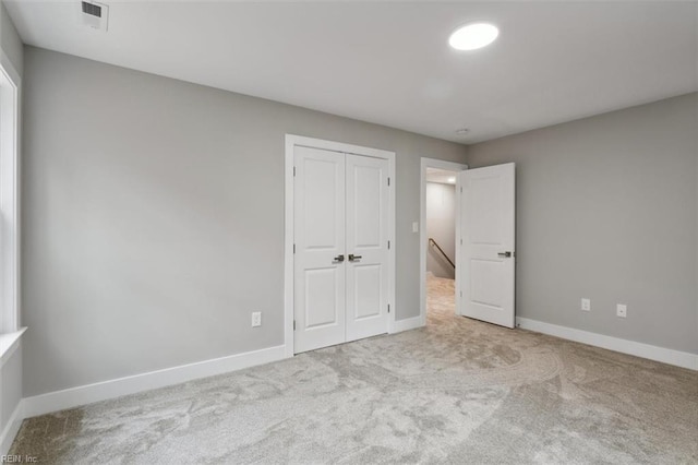 unfurnished bedroom featuring light carpet and a closet