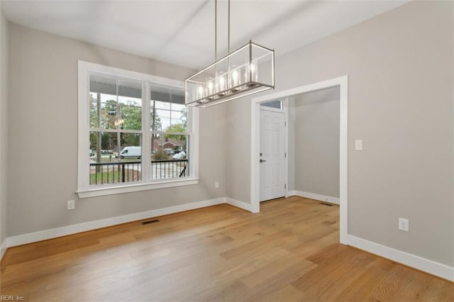 unfurnished dining area featuring hardwood / wood-style floors and a chandelier