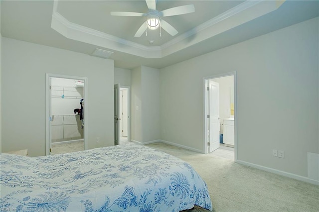 bedroom with ensuite bath, ceiling fan, a raised ceiling, a walk in closet, and light carpet