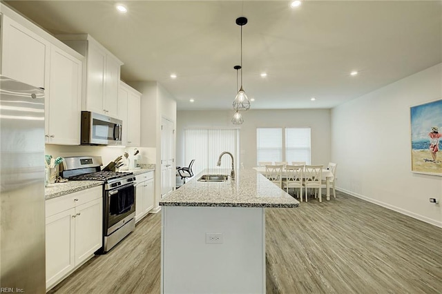 kitchen with white cabinets, sink, stainless steel appliances, and a kitchen island with sink