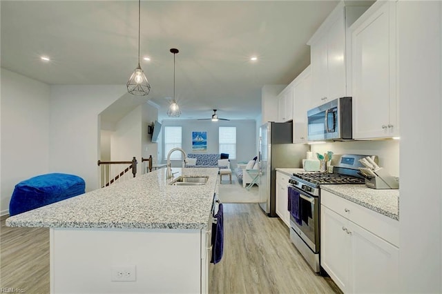 kitchen featuring decorative light fixtures, white cabinetry, an island with sink, and appliances with stainless steel finishes