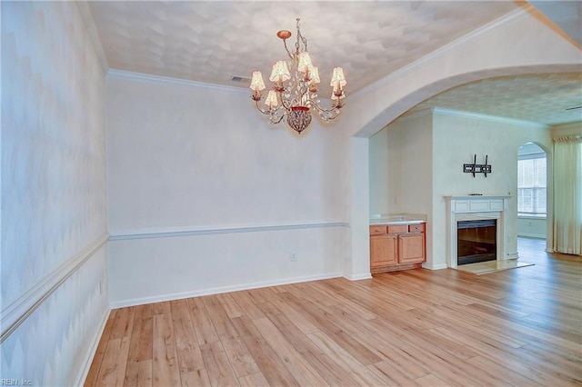 interior space with light wood-type flooring, crown molding, and a chandelier