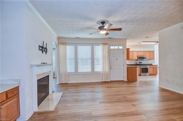 unfurnished living room featuring a high end fireplace, crown molding, ceiling fan, a textured ceiling, and light hardwood / wood-style floors