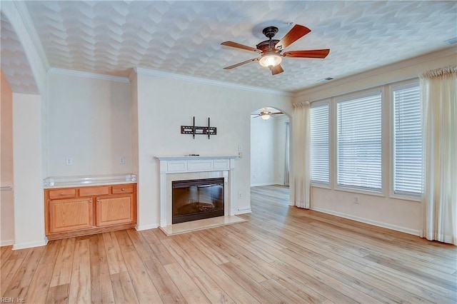 unfurnished living room featuring light wood-type flooring, ceiling fan, ornamental molding, and a premium fireplace