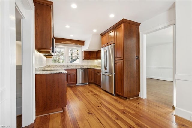 kitchen with light hardwood / wood-style floors, light stone countertops, and stainless steel appliances