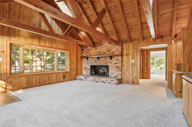 unfurnished living room with a fireplace, wood walls, light carpet, and a wealth of natural light