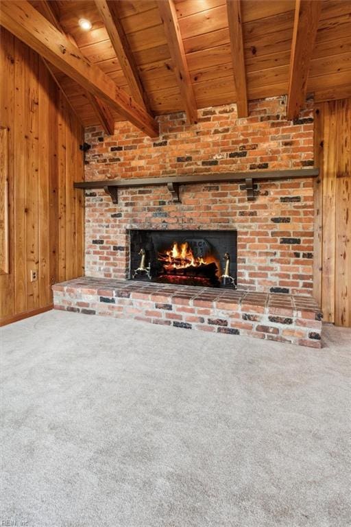 unfurnished living room with wooden walls, beamed ceiling, carpet floors, and wooden ceiling