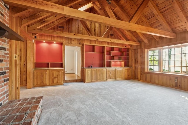 unfurnished living room featuring beam ceiling, light colored carpet, and wooden walls