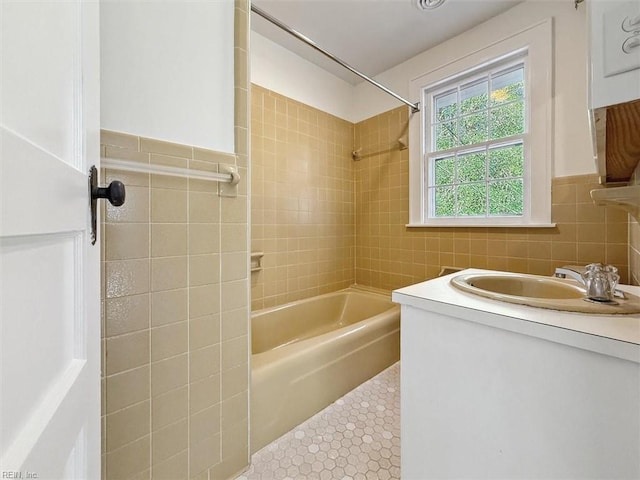 bathroom featuring tile patterned floors, vanity, tiled shower / bath combo, and tile walls