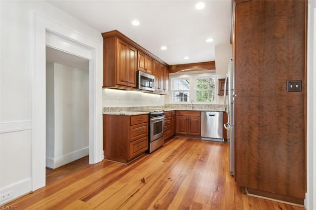 kitchen with light hardwood / wood-style floors, sink, light stone countertops, and stainless steel appliances