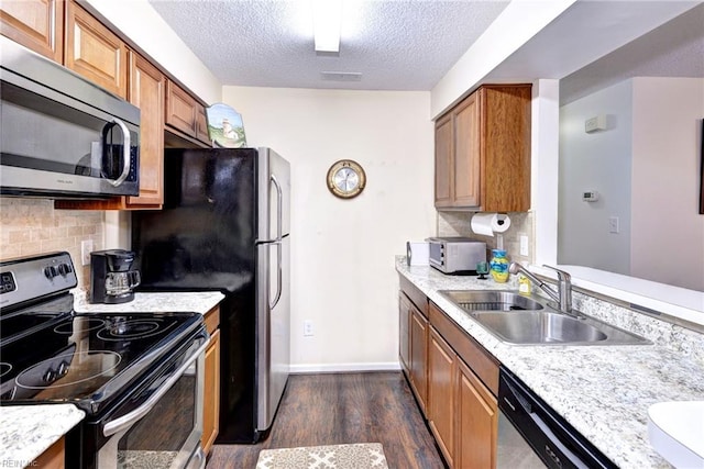 kitchen with backsplash, dark wood-type flooring, sink, a textured ceiling, and appliances with stainless steel finishes